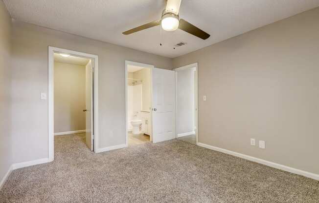 a bedroom with light colored walls and carpet and modern ceiling fan looking into a bathroom at Veridian Sandy Springs