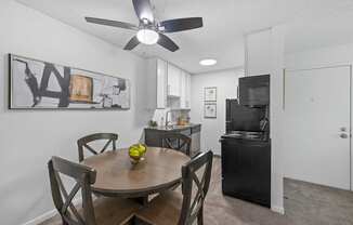 a dining area with a table and chairs and a kitchen in the background