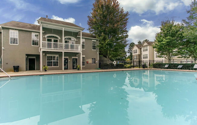 A large swimming pool in front of a two-story building with a balcony.