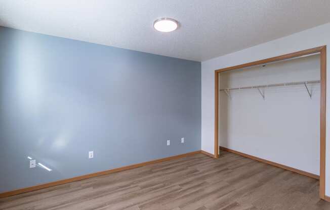 a room with a door to a closet and a hard wood floor. Fargo, ND Sunwood Apartments