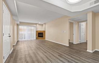 an empty living room with a fireplace and wood flooring