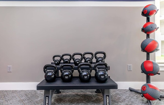 A set of kettlebells are arranged on a bench in a room.