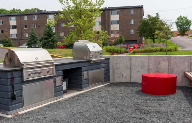 an outdoor kitchen with a red stool in front of a brick building