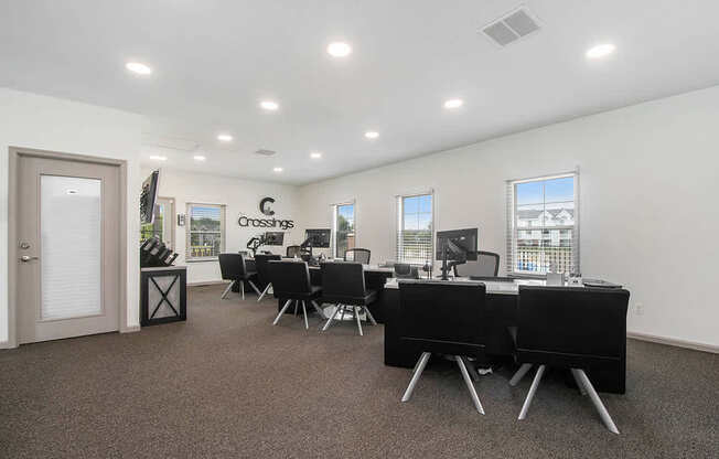 A leasing office with a carpeted floor and desks with chairs at The Crossings Apartments in Grand Rapids, MI