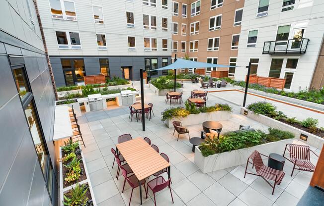The landscaped courtyard features outdoor dining areas, comfortable lounge seating, shaded gathering spaces, and thoughtfully designed green areas that encourage connection, relaxation, and outdoor enjoyment.