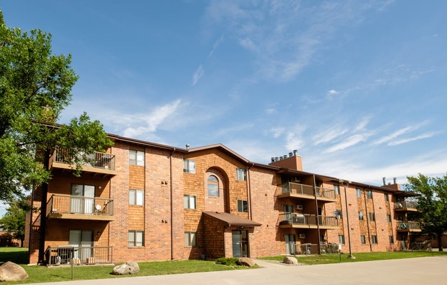 a brick apartment building with balconies and a blue sky. Fargo, ND Southview Village Apartments