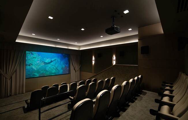 A row of black chairs are set up in front of a large screen.