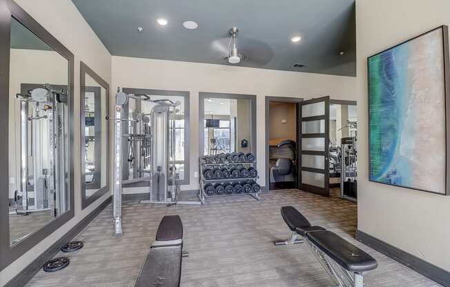 a fitness room with cardio machines and a large painting on the wall