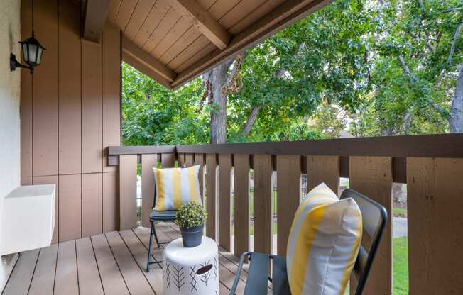 a covered porch with two chairs and a table