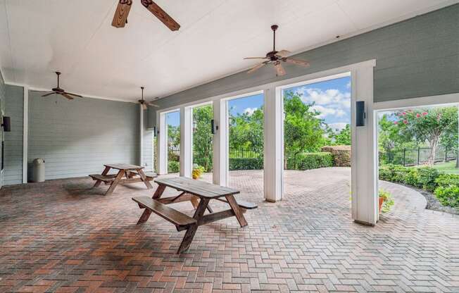 a covered patio with two picnic tables and two ceiling fans at St. Augustine Estate, Dallas, TX 75227