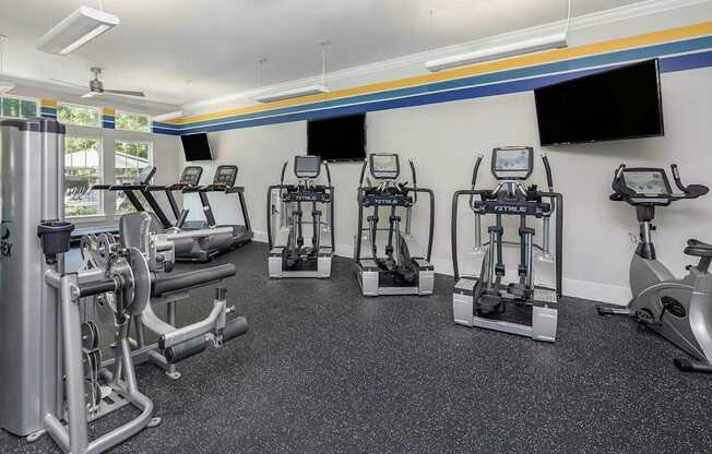 A gym with a variety of equipment including treadmills, stationary bikes, and weight machines.