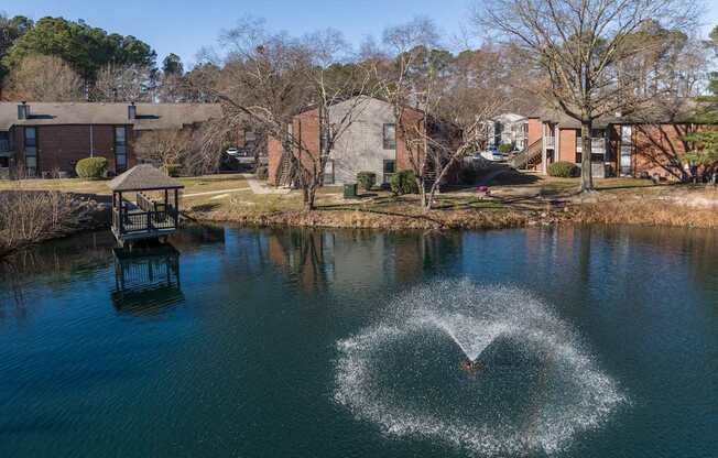 A fountain in the middle of a lake in a residential area.