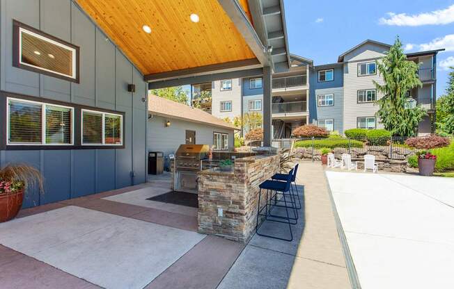 A patio area with a stone wall and a wooden roof.