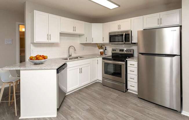 A modern kitchen with stainless steel appliances and white cabinets.at Prosper West, Waite Park Minnesota
