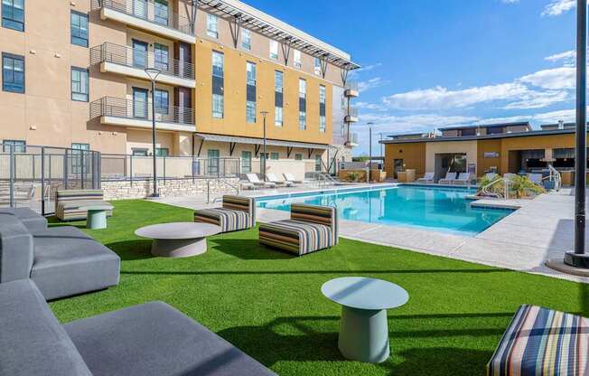 A large outdoor area with a pool, lounge chairs, and a building in the background.