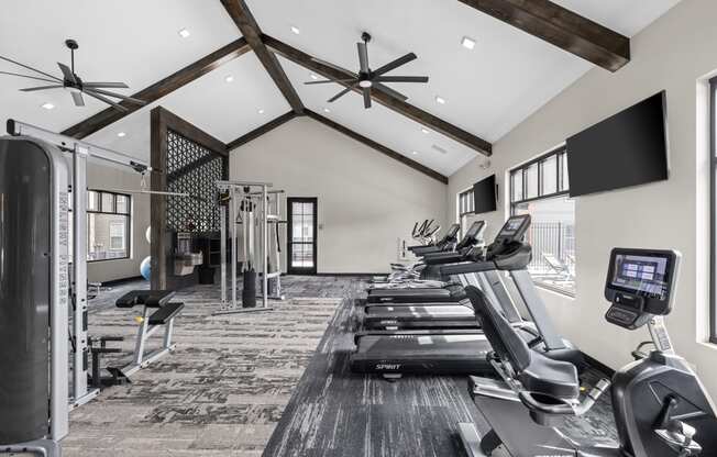 a gym with treadmills and weights and a tv