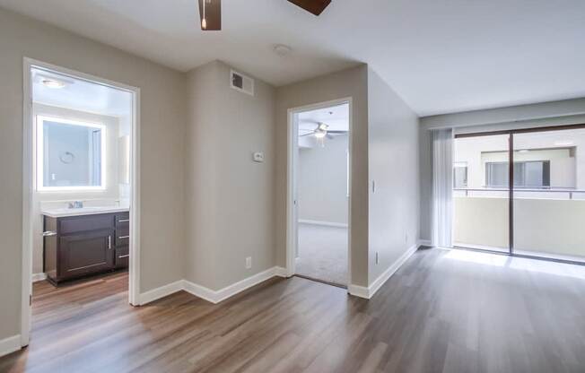 A room with a ceiling fan and sliding glass doors.