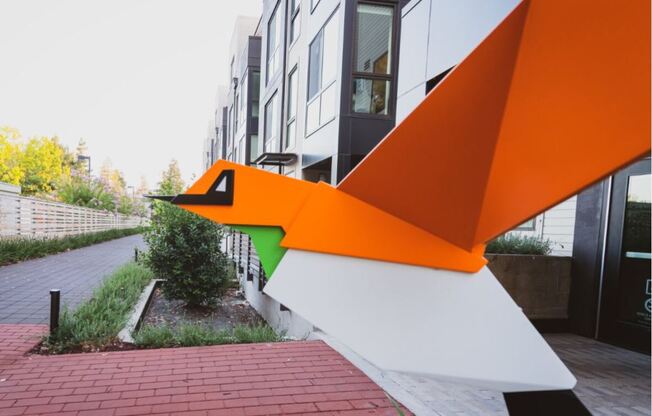 an orange and white sculpture in front of a building