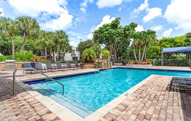 a swimming pool with trees and chairs around it at Waterford Park Apartment Homes, LLC, Lauderhill, FL 33319