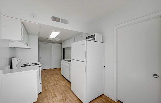 A white kitchen with a stove, refrigerator, and oven.