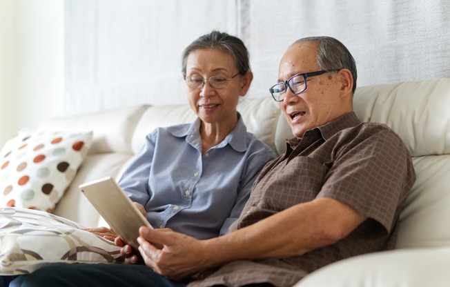 woman and man sitting on a couch and looking at a tablet