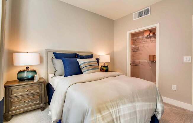 A bedroom with a large bed and a nightstand with a lamp.