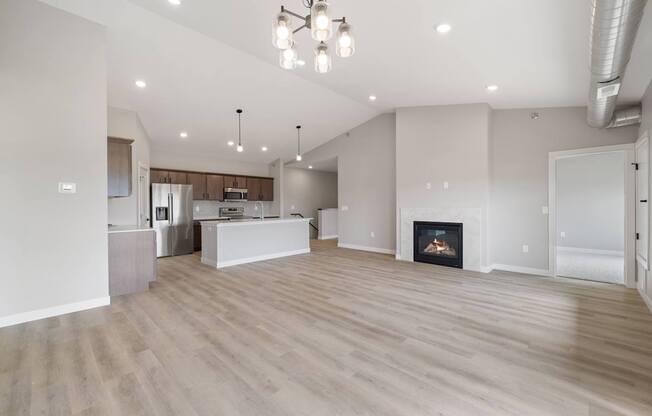 A spacious living room with a fireplace and a kitchen in the background.