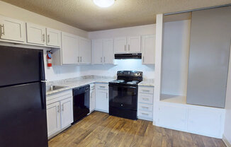 A kitchen with black appliances and white cabinets.