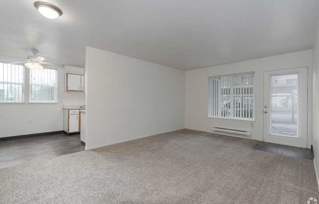 A spacious room with a carpeted floor and a window with blinds.