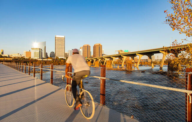 a man riding a bike on a bridge with a city in the background