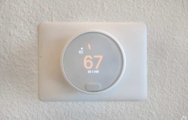 A thermostat showing a temperature of 67 degrees.
