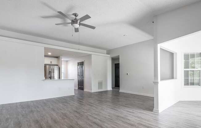 an empty living room and kitchen with a ceiling fan