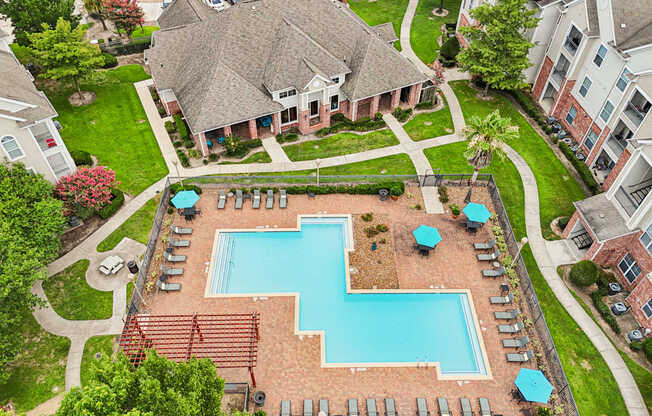 A large swimming pool surrounded by a brick wall and lounge chairs.