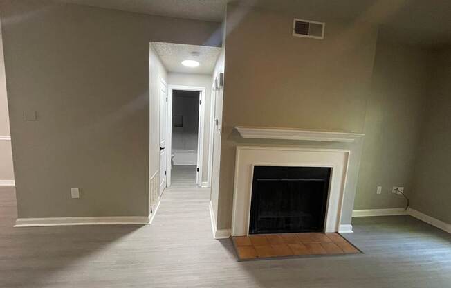 A room with a fireplace and a doorway leading to another room.