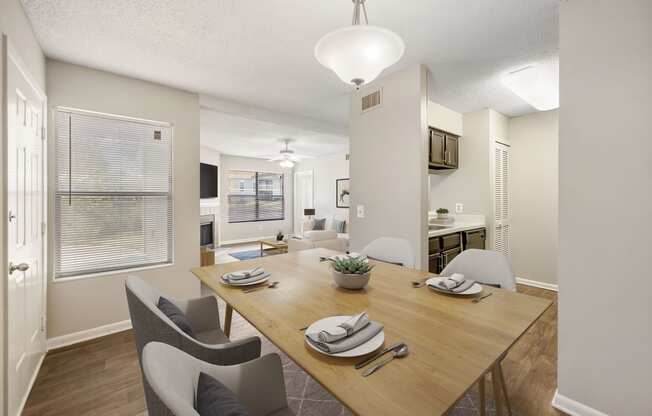 a dining area with a wooden table and chairs and a kitchen in the background