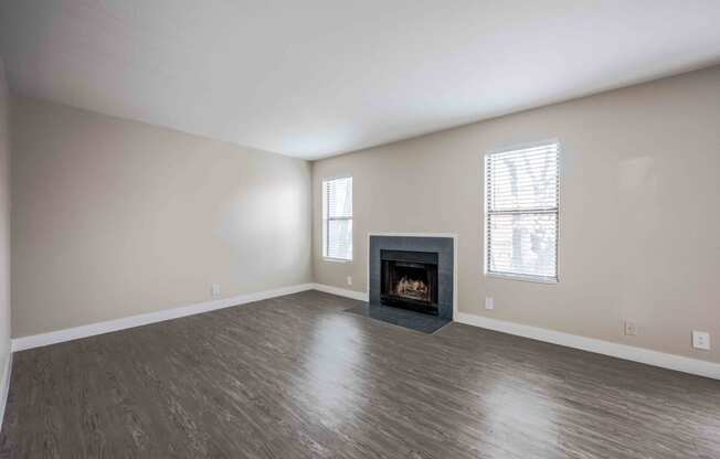 an empty living room with a fireplace and wooden floors