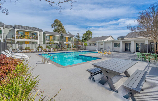 a swimming pool with a picnic table and chairs around it