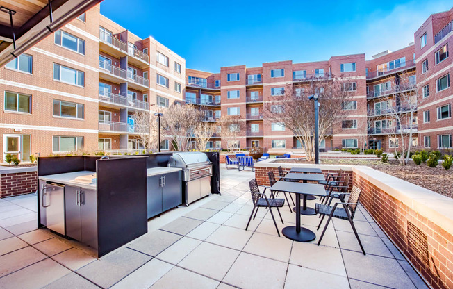 an outdoor patio with tables and chairs and a large apartment building