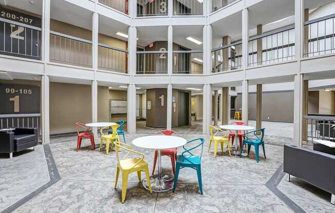 A courtyard with tables and chairs and apartment numbers.