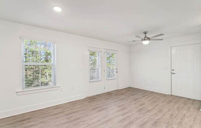 A room with a ceiling fan and two windows with blinds.