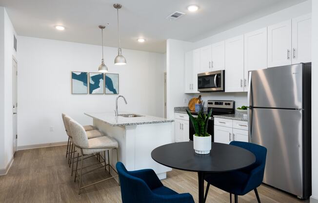 a kitchen and dining area with stainless steel appliances and a table and chairs