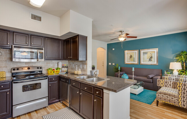 View of Kitchen with Stainless Steel Appliances, Plank-Wood Flooring, and View of Living Room at Ravneaux Apartments