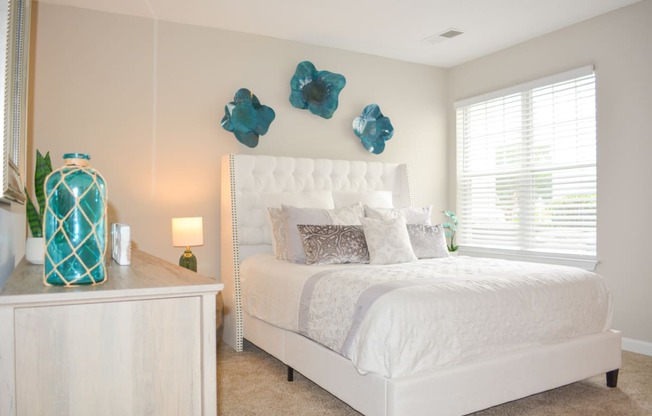 a bedroom with a white bed and blue flowers on the wall