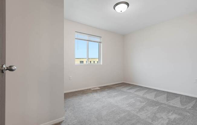 A room with a carpeted floor and a window.