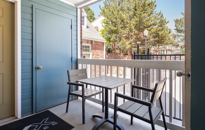 a balcony with a table and chairs and a blue door