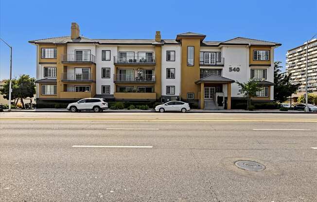 A street view of a building with cars parked in front.