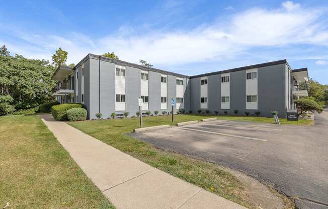 A large grey building with a parking lot in front.