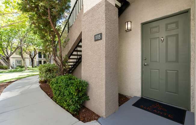 the front door of an apartment building with a sidewalk and a green door