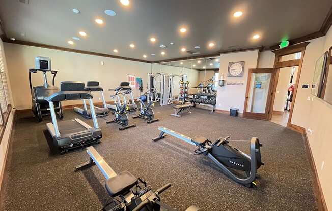 a gym with cardio equipment and weights on the floor