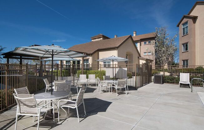 a patio with tables and umbrellas and a building in the background  at Seville at Gale Ranch, California